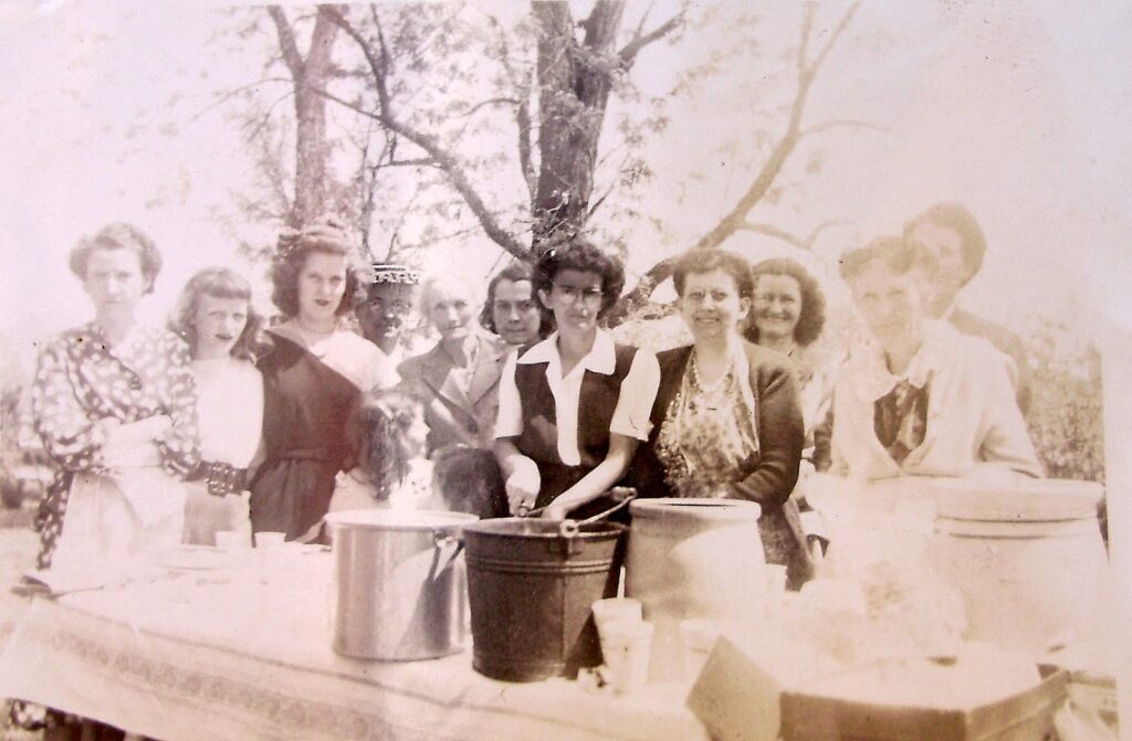 Old family photo with a group of women at a table full of food.