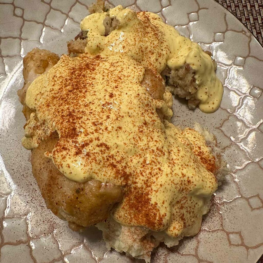 Cooked chicken covered with yellow sauce and sprinkled with paprika