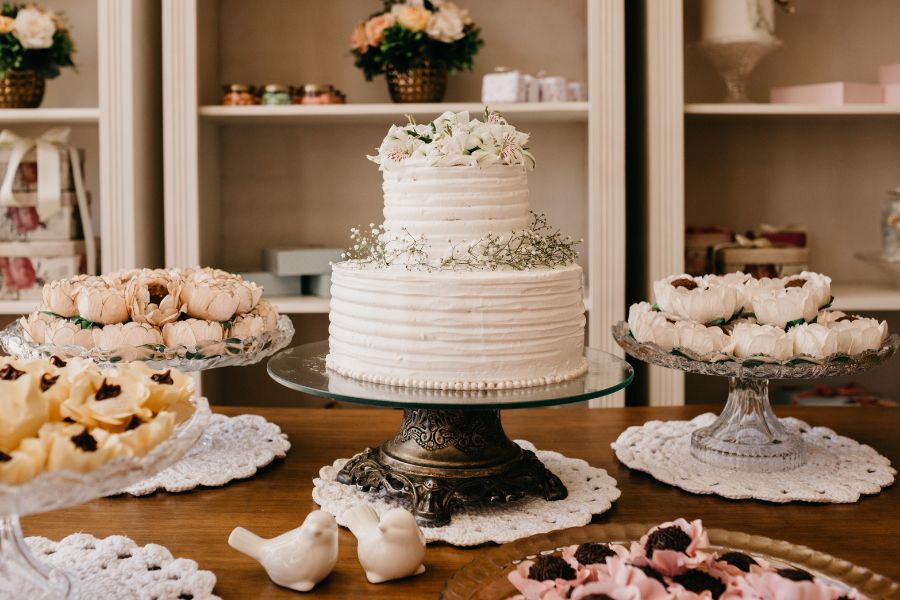 2 tier wedding cake with flowers on top. Other small bites on plate.