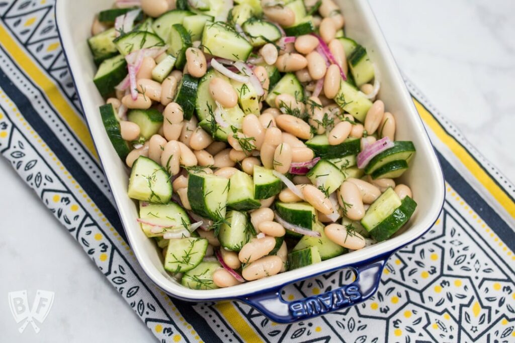 Cucumber and white bean salad on blue and yellow tea towel