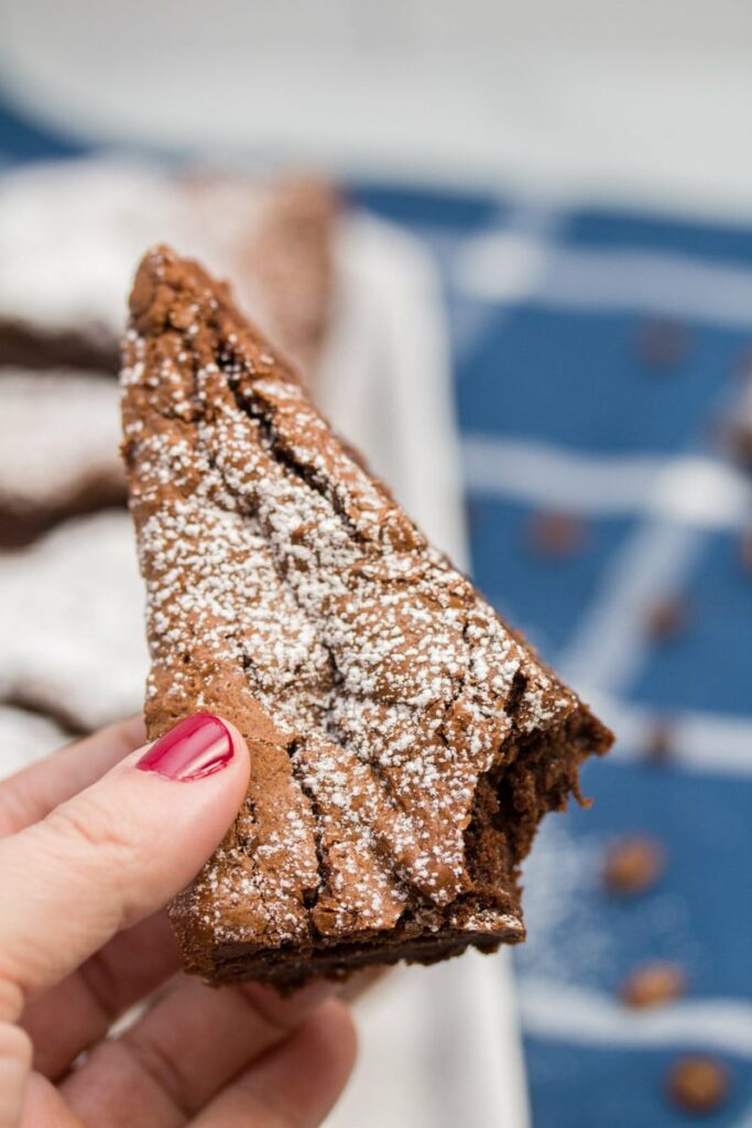 Hand holding brownie with one bite taken