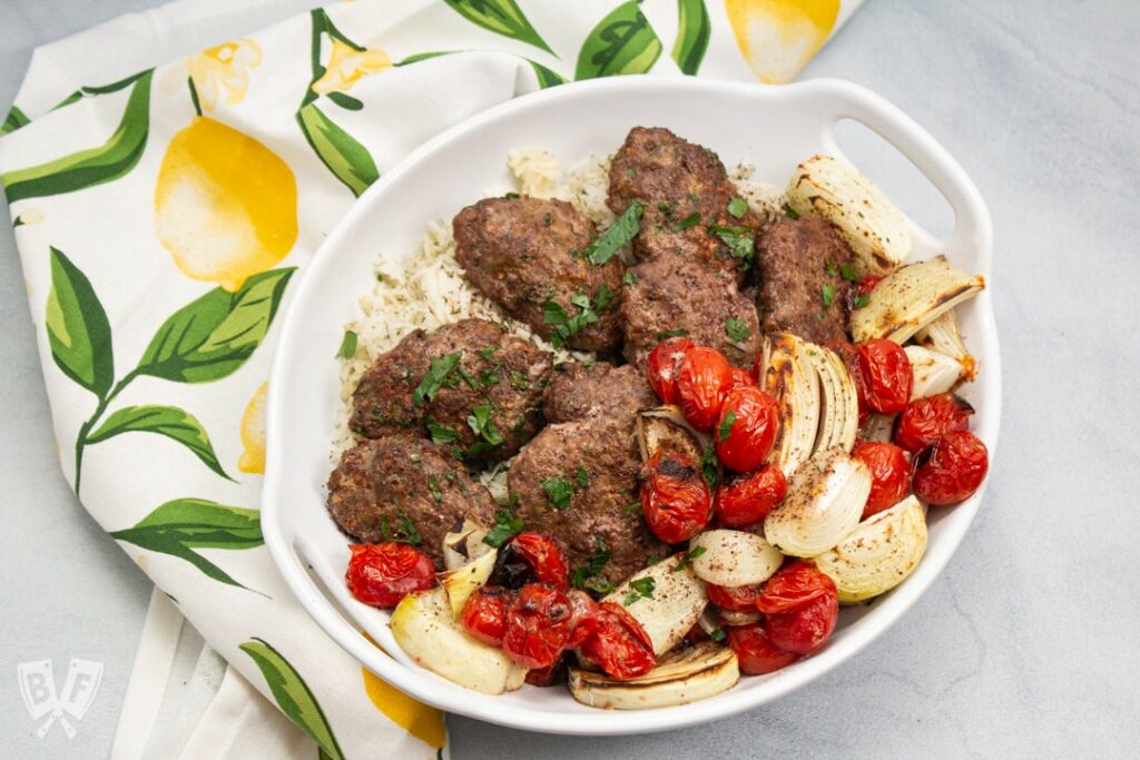 Kabobs with tomatoes and onions in a white dish on a lemony tea towel