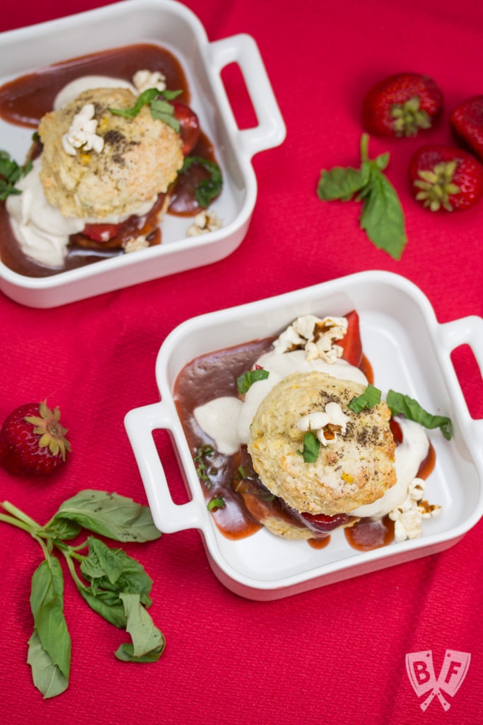2 strawberry shortcakes each in a white bowl and on a red tablecloth