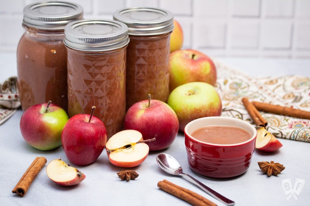 Jars of applesauce and red apples around them